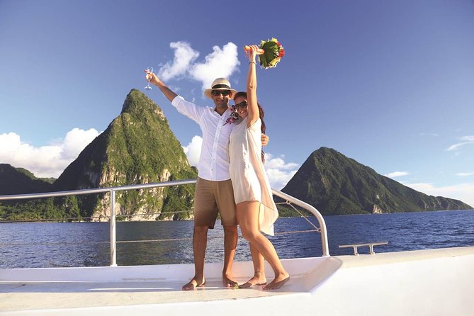 Couple on a boat deck celebrate with arms raised, woman holding a bouquet, sea and green karst islands in the background.